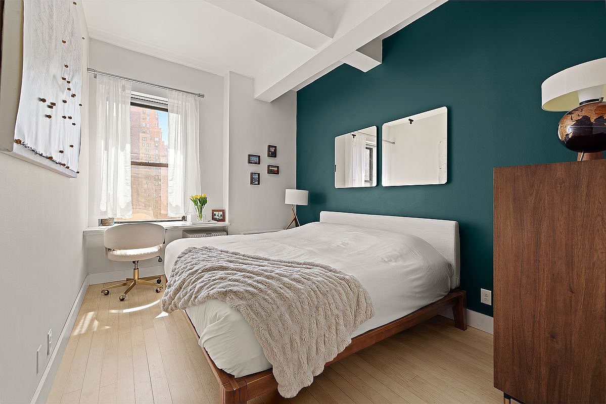 Primary bedroom at 150 Joralemon 11E, eastern morning light coming through the gauze curtain, beamed ceiling, teal accent wall and hardwood floors
